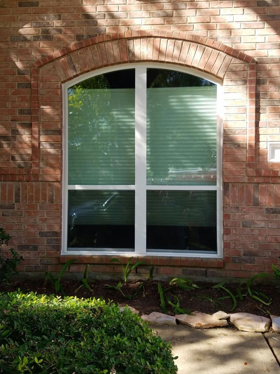 custom arched window on intricately bricked residential home