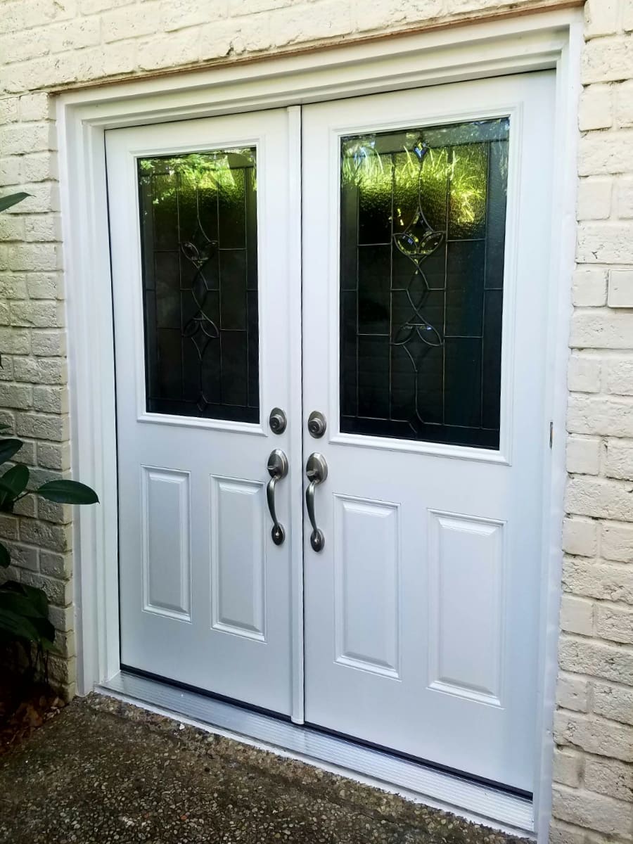 modern white exterior french doors on a beige brick home