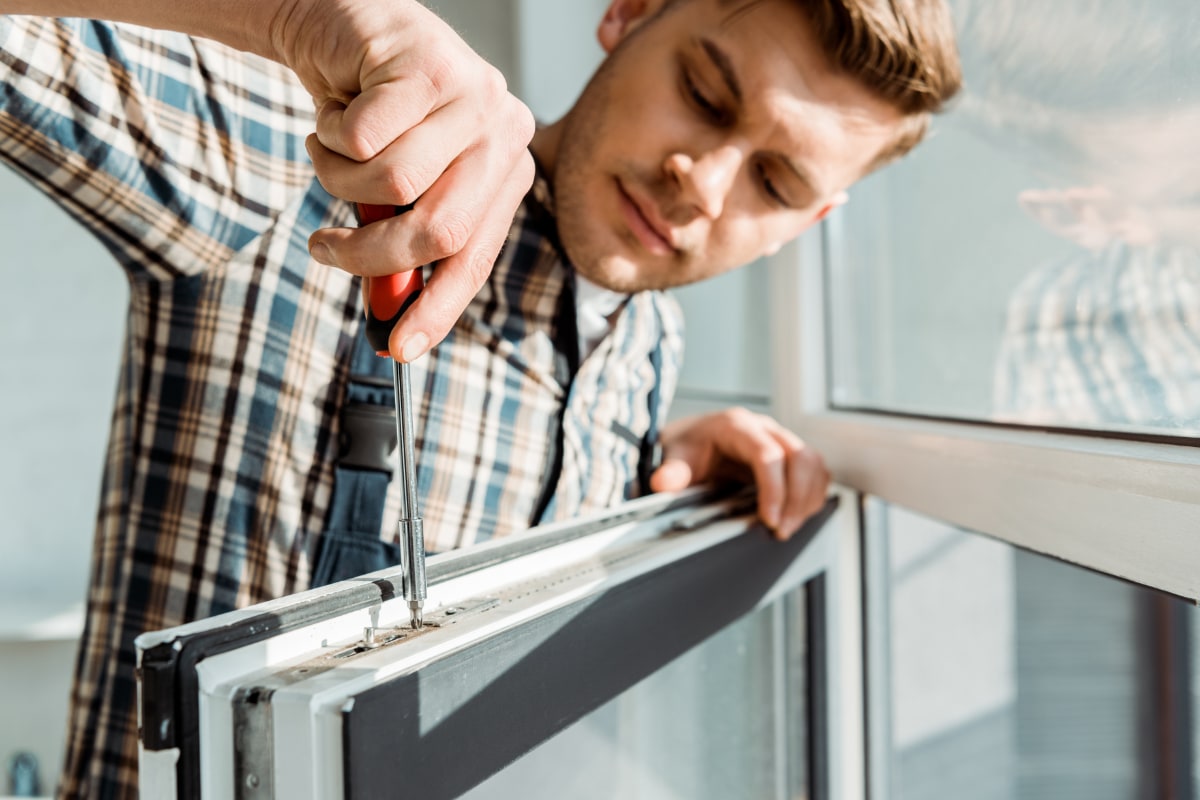 window installer screwing in a screw in the top of a window